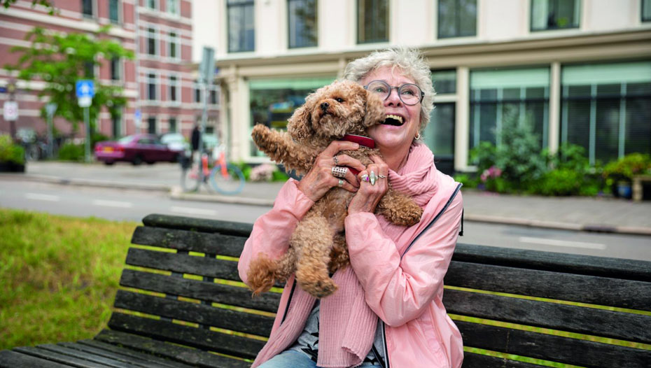 Дама вдига куче на пейка в парка
